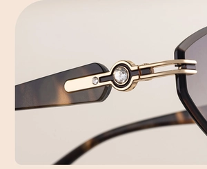 Détail macro de la branche de lunettes en écaille avec charnière dorée et strass brillants