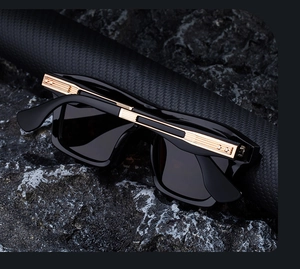 Detail of square polarized sunglasses with gold metal bar accents on black frame
