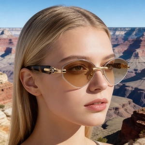 Détail de lunettes de soleil œil-de-chat avec branches dorées et verres dégradés marron