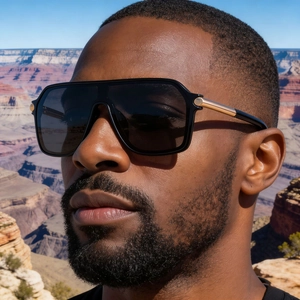 Homme portant lunettes de soleil carrées oversize avec branches dorées dans un canyon