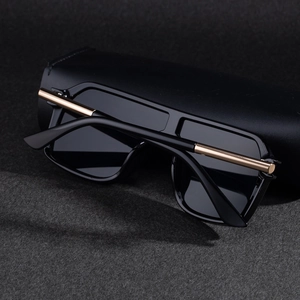 Détail de lunettes de soleil noires carrées avec garniture dorée et étui en cuir