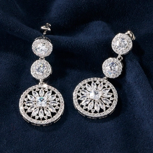 Macro shot of silver tassel earrings with white zircon stones on blue velvet base