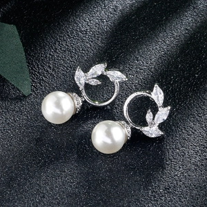 Macro shot of silver pearl earrings with marquise zircon leaves on black fabric
