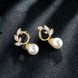 Close-up of gold tassel earrings with zircon marquise leaves and round pearls