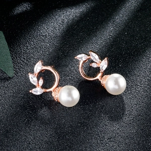 Detail of rose gold tassel earrings with zircon leaf design and round white pearls