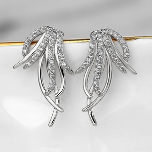 Close-up of silver tassel earrings with micro-set zircons on a white porcelain tray