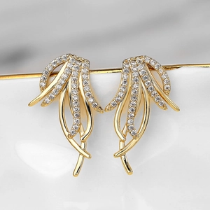 Detailed macro shot of gold tassel earrings with zircon pavé on a ceramic edge