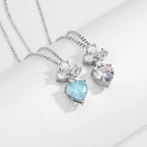 Gros plan de pendentifs cœur en cristal bleu et blanc avec feuilles en zircon marquise
