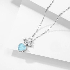 Détail d'un collier cœur en argent avec pierre bleu clair et motif de trèfle