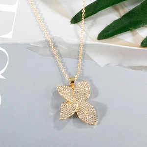 Close-up of gold clover necklace with micro-pave cubic zirconia on gray background