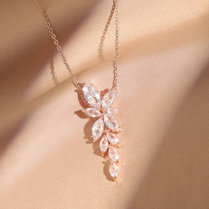 Collier avec pendentif feuille en or rose et zircons sur tissu en soie couleur champagne