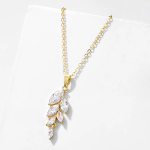 Détail d'un collier feuille dorée serti de zircones marquises sur un support minimaliste