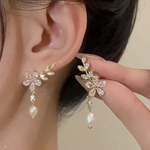 Vue détaillée de boucles d'oreilles fleur dorées avec zircons et perles en goutte
