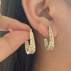 Gros plan de boucles d'oreilles dorées en C avec micro-strass sur une oreille