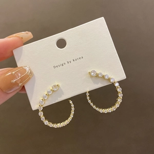 Boucles d'oreilles créoles dorées en C avec oxydes de zirconium sur carte blanche