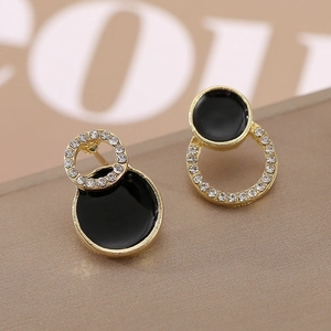 Vue macro de boucles d'oreilles géométriques dorées avec émail noir et cristaux blancs