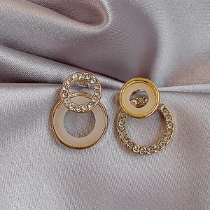 Vue détaillée de boucles d'oreilles doubles avec finition dorée, émail beige et cristaux