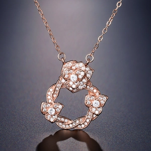 Collier couronne de camélia en or rose serti de zircons brillants sur fond dégradé bleu