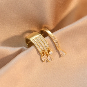 Macro detail of luxury gold tassel earrings with drop crystals on champagne silk fabric