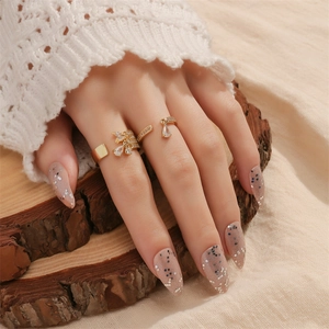 Close-up of gold water drop fringe rings and layered pavé set on wooden surface
