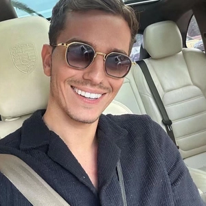 Close-up of golden hexagonal metal sunglasses with purple gradient lenses worn in a car