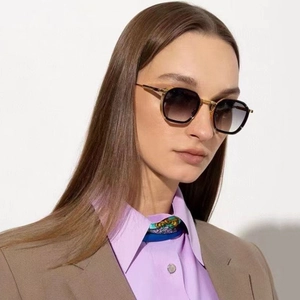Close-up of golden geometric frame sunglasses with dark grey gradient lenses on a model