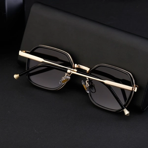 Detail of square sunglasses with gold metal temples on a textured black hard case