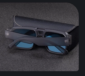 Close-up of matte black aviator sunglasses with light blue lenses on a leather case