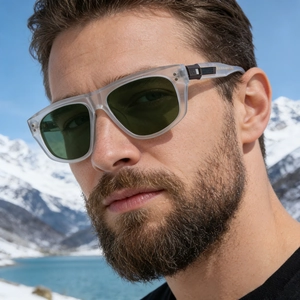 Close-up of frosted clear sunglasses with green lenses worn in a snowy mountain setting