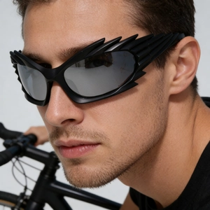 Detail of wing-shaped sunglasses with silver mirrored lenses on a model's profile