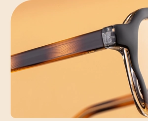 Macro view of metal hinges and amber gradient acetate temples on square sunglasses