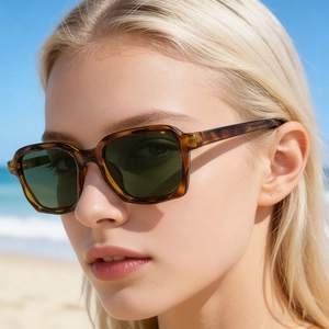 Lunettes de soleil carrées en écaille avec verres verts portées sur une plage d'été