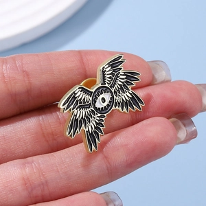 Detailed close-up of a gothic four-winged eye enamel brooch with gold-plated alloy trim