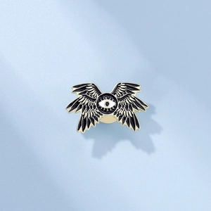 Detail of dark gothic eagle eye enamel pin with multi-winged design on blue texture