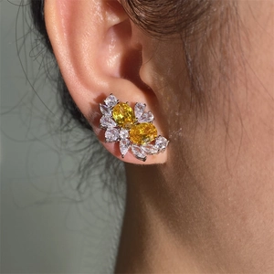 Elegant silver earrings with yellow oval gemstones and clear zircon clusters on ear