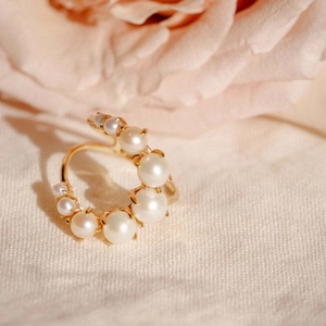 Elegant multi-layer spiral ring with gradient pearls and gold finish on a soft background
