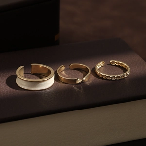 Three-piece gold-tone adjustable rings featuring turquoise and chain designs on leather box