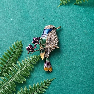 Exquisite Kolibri-Brosche mit Kristall und Emaille auf grünem Blätterhintergrund