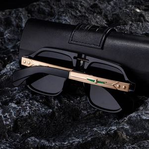 Detail of square polarized sunglasses with gold temples and star relief on rocky surface