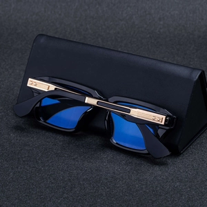 Close-up of square sunglasses with blue lenses and gold metal accents on a leather case