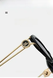 Detail of black frame sunglasses showing gold metal temple with hollow circular logo