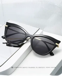 Detail of black cat-eye sunglasses with gold metal hinges on a stylish glass background