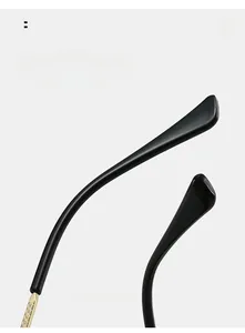 Close-up of black curved temple tips with golden textured metal spring hinges on sunglasses