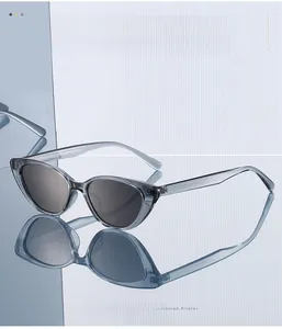 Detail view of transparent grey cat-eye sunglasses with dark grey lenses and clear reflections