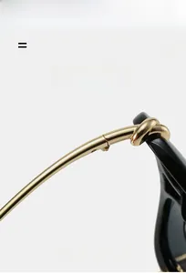 Gros plan de la charnière en métal doré avec nœud unique sur lunettes aviateur noires