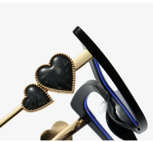 Detail of cat eye glasses frame with heart-shaped decor and golden metal temples