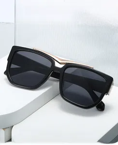 Detail of square oversized black sunglasses with a stylish gold metal bridge bar accent