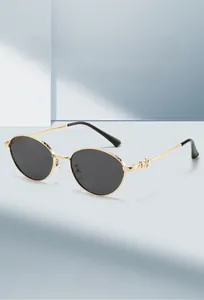 Detail of gold metal oval sunglasses frame with intricate engraved texture and dark lenses