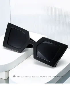 Detail view of bold black hexagonal oversized sunglasses on a minimalist white display