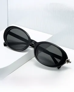 Detail of oval sunglasses with black frame and silver ball accents on temple tips